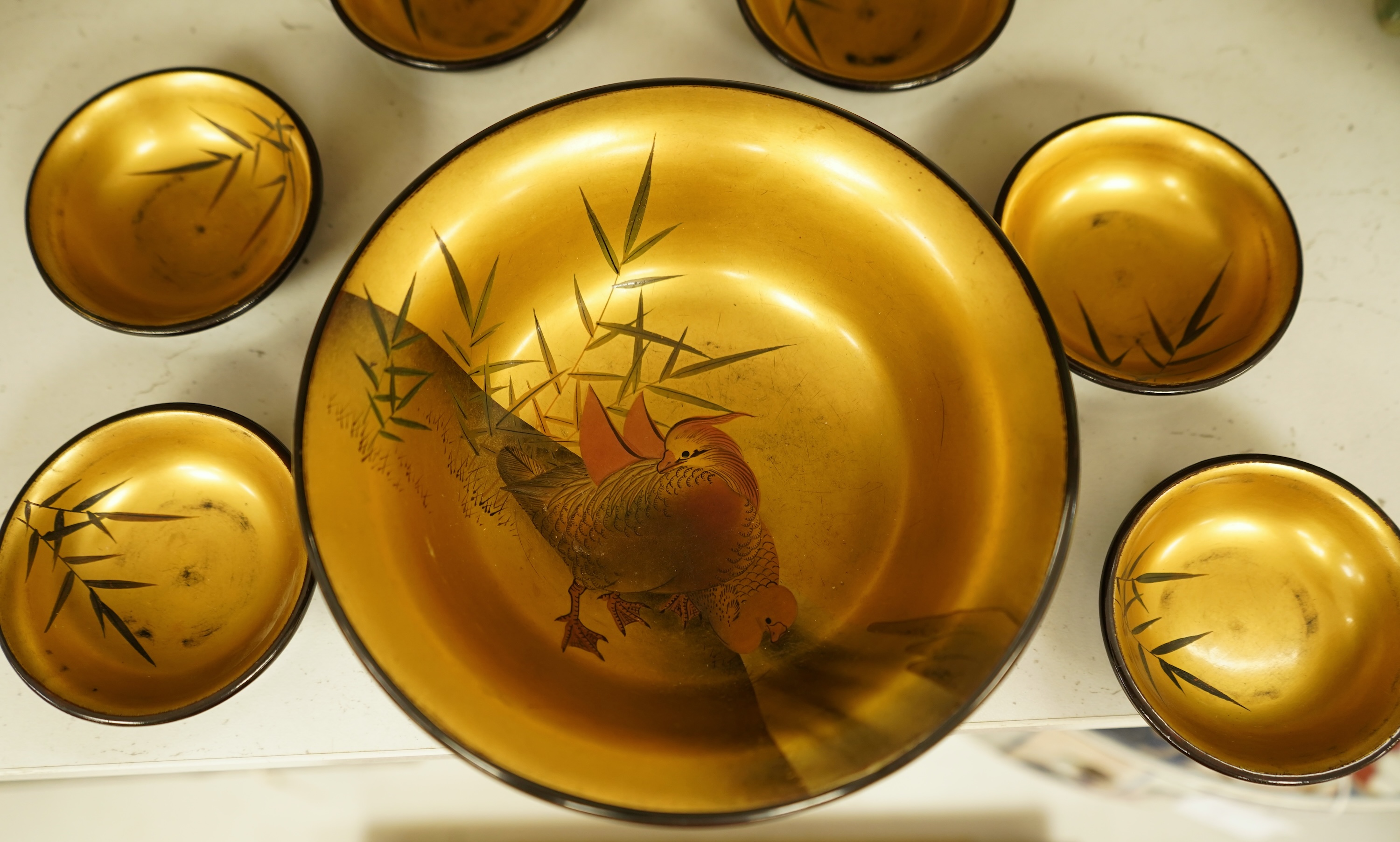 A Japanese lacquer bowl with gilt interior decorated with birds and six small dishes, largest 15cm in diameter